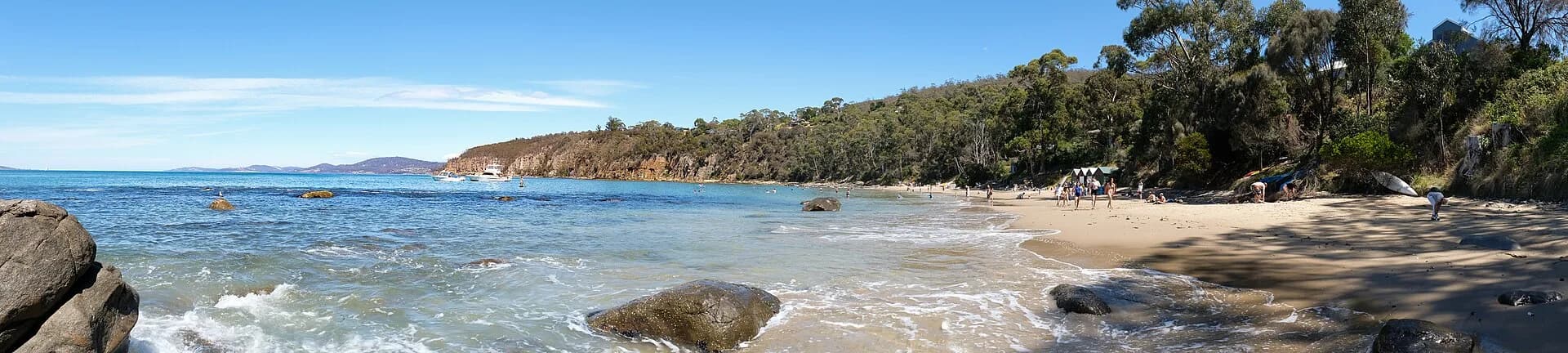 Sand, rocks and calm water at Hinsby Beach in Taroona